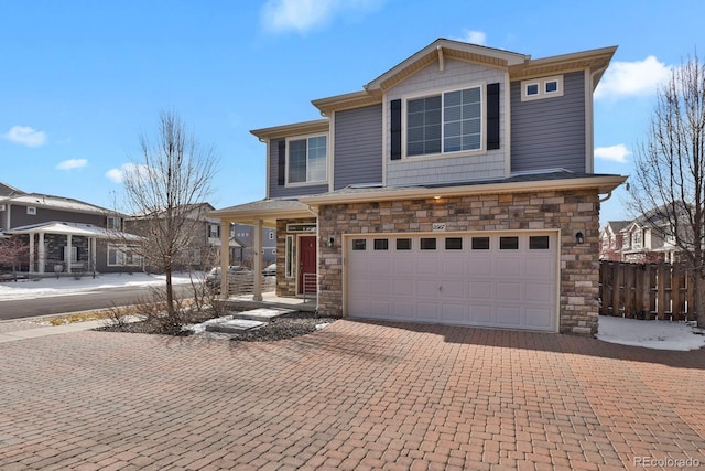 view of front of house with stone siding, decorative driveway, an attached garage, and fence