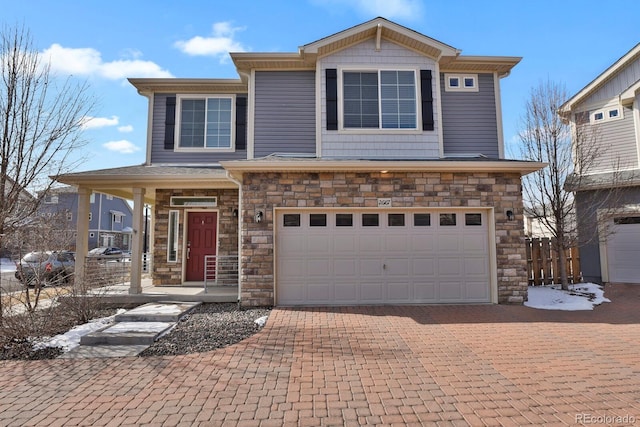 view of front of house with stone siding, decorative driveway, an attached garage, and fence