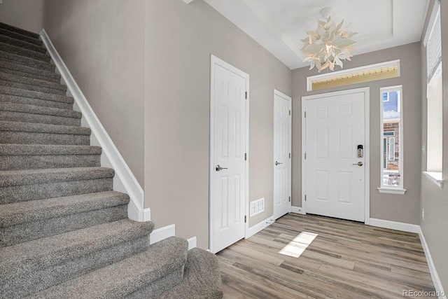 foyer featuring visible vents, stairs, baseboards, and wood finished floors