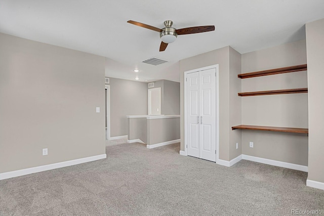 empty room with light carpet, a ceiling fan, visible vents, and baseboards