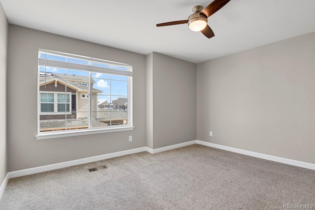 carpeted spare room featuring ceiling fan, visible vents, and baseboards