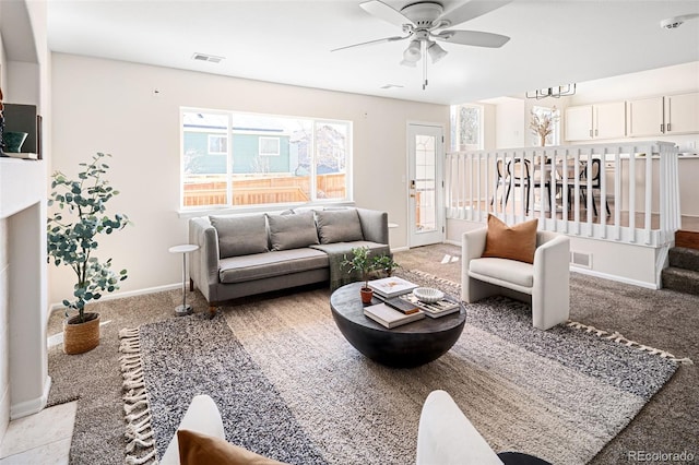 living area with baseboards, visible vents, and a ceiling fan