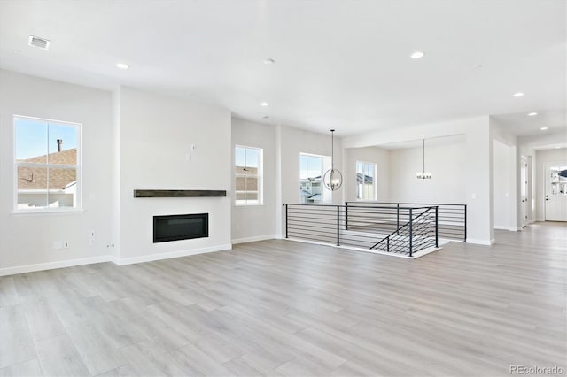 unfurnished living room with a notable chandelier and light hardwood / wood-style flooring