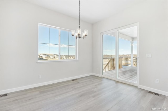 empty room featuring a chandelier and light hardwood / wood-style flooring