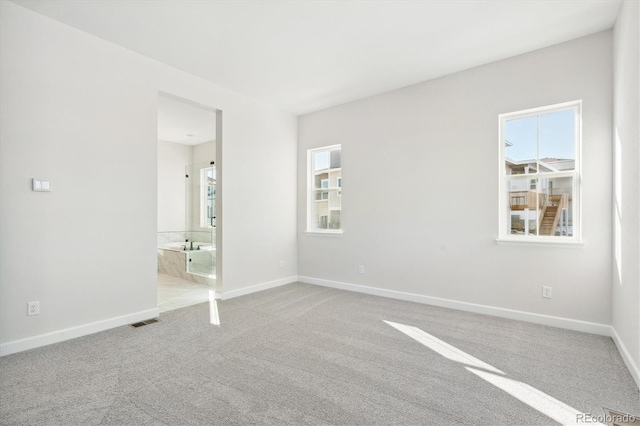 unfurnished bedroom featuring light colored carpet and ensuite bath