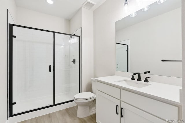 bathroom featuring hardwood / wood-style flooring, vanity, toilet, and a shower with shower door