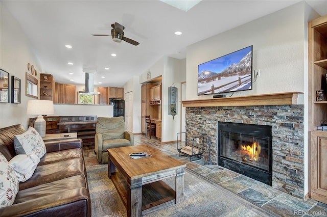 living room featuring a ceiling fan, a stone fireplace, and recessed lighting