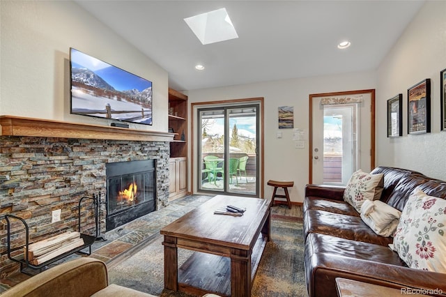 living room featuring plenty of natural light, built in features, a skylight, and a stone fireplace
