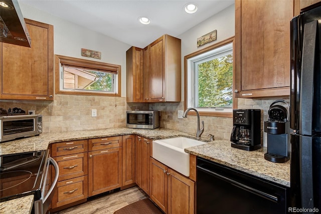 kitchen with a sink, black appliances, plenty of natural light, and a toaster
