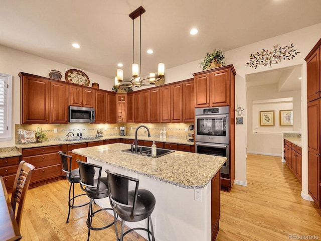 2571 Hunters Pl, Highlands Ranch, CO 80129 - kitchen with appliances with stainless steel finishes, a sink, a center island with sink, tasteful backsplash, and a chandelier