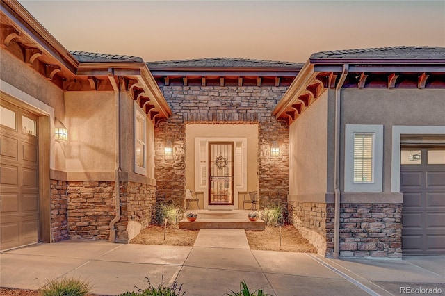 2571 Hunters Pl, Highlands Ranch, CO 80129 - exterior entry at dusk with stone siding, stucco siding, and a tiled roof