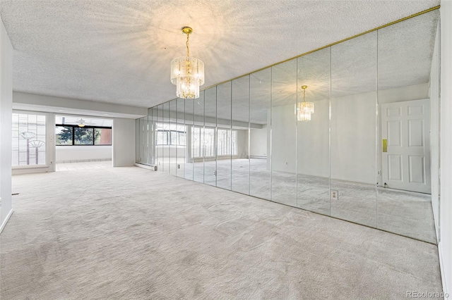 unfurnished living room with carpet flooring, a textured ceiling, ceiling fan with notable chandelier, and baseboard heating