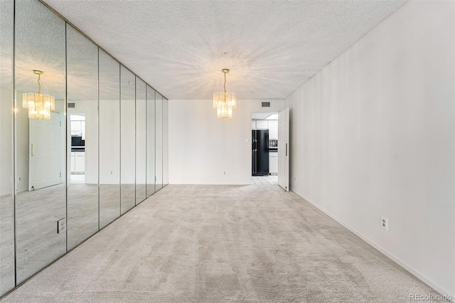 carpeted spare room with a chandelier and a textured ceiling