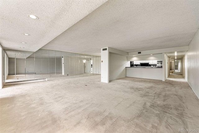 unfurnished living room featuring light carpet, a textured ceiling, and baseboard heating