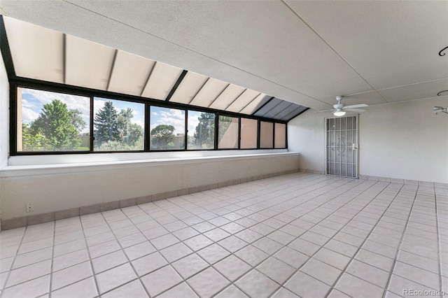 empty room with ceiling fan, light tile patterned floors, and vaulted ceiling