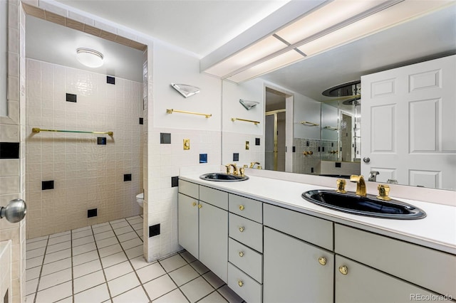 bathroom with tile patterned floors, an enclosed shower, vanity, tile walls, and toilet