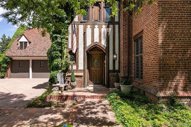 view of exterior entry featuring concrete driveway and brick siding