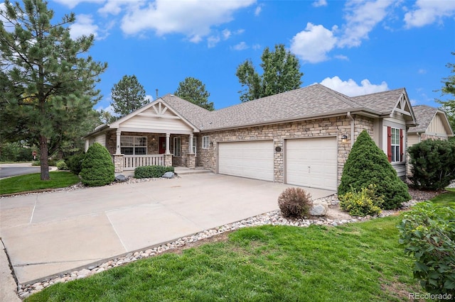 view of front of home featuring a porch, an attached garage, stone siding, driveway, and a front lawn