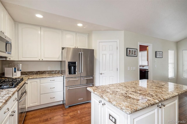 kitchen with appliances with stainless steel finishes, wood finished floors, recessed lighting, and light stone countertops