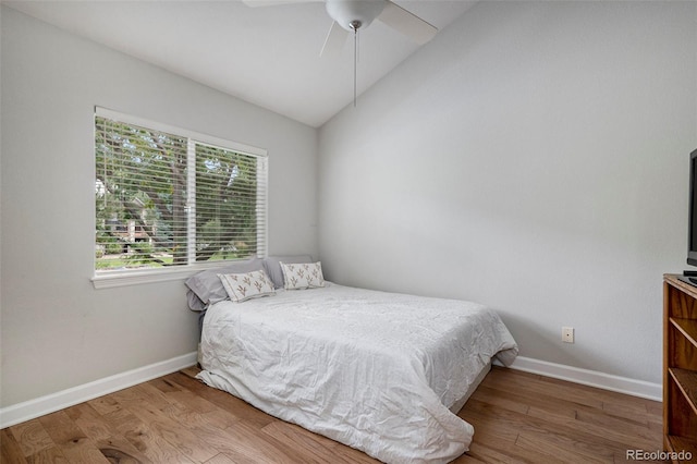 bedroom featuring wood finished floors, vaulted ceiling, baseboards, and ceiling fan