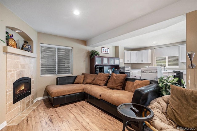 living room with light wood-style flooring, baseboards, a lit fireplace, and recessed lighting