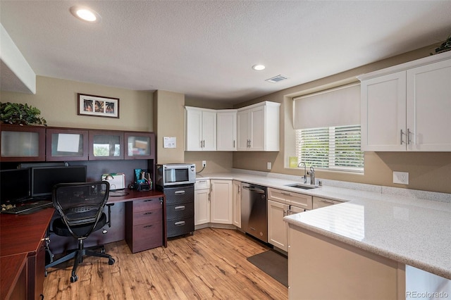 kitchen featuring appliances with stainless steel finishes, a sink, light wood finished floors, white cabinetry, and recessed lighting