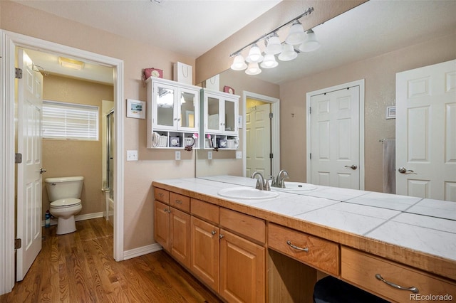 full bath featuring wood finished floors, toilet, vanity, and baseboards