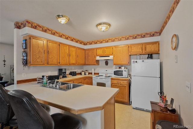 kitchen featuring sink, white appliances, a kitchen breakfast bar, and kitchen peninsula