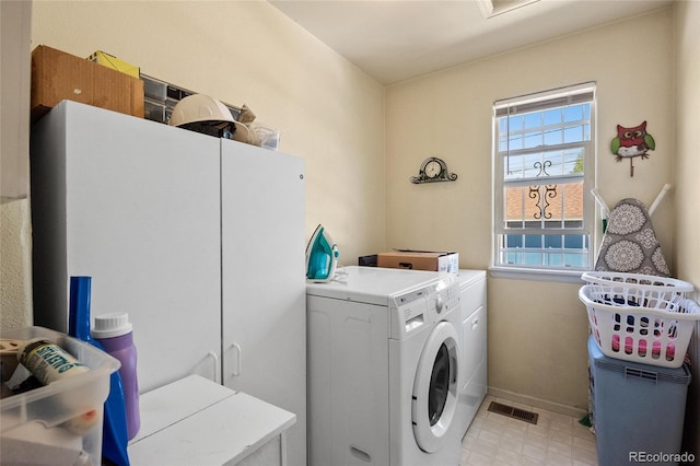 washroom featuring washer and dryer, cabinets, and a healthy amount of sunlight