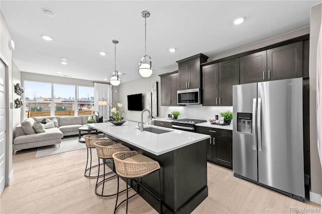 kitchen featuring appliances with stainless steel finishes, sink, pendant lighting, an island with sink, and a breakfast bar area