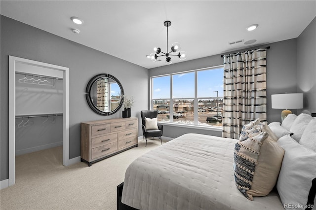 bedroom with a notable chandelier, light carpet, a closet, and a walk in closet