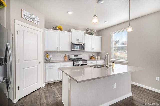 kitchen featuring a center island with sink, pendant lighting, white cabinets, and stainless steel appliances