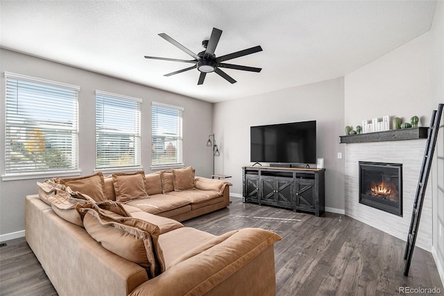 living room featuring a textured ceiling, ceiling fan, a fireplace, and dark hardwood / wood-style flooring