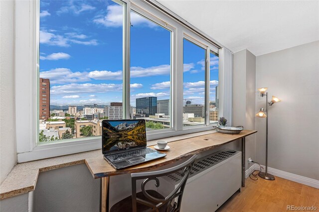 office space featuring a city view, baseboards, and light wood-type flooring