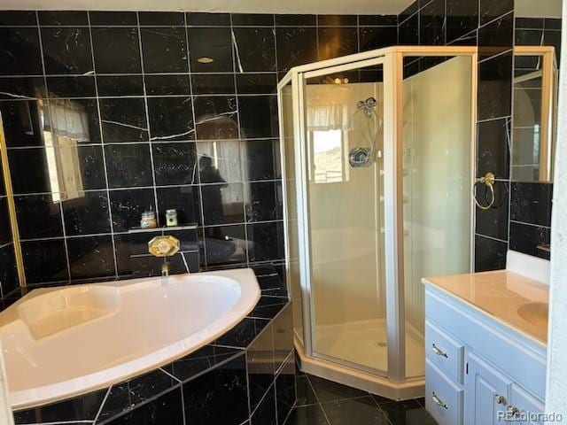 bathroom featuring tile patterned floors, independent shower and bath, vanity, and tile walls