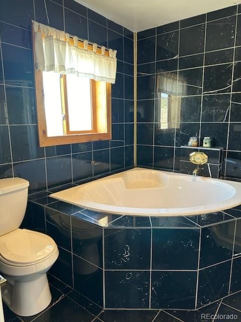 bathroom featuring a wealth of natural light, toilet, tile patterned flooring, and tile walls