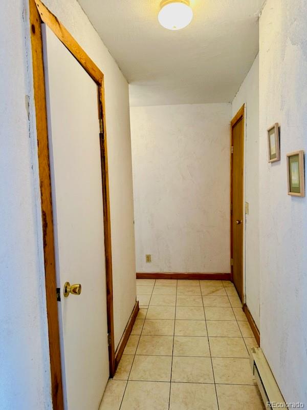 hallway featuring light tile patterned floors and a baseboard heating unit