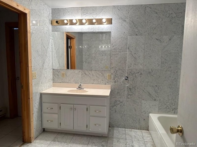 bathroom with vanity, a bathing tub, tile patterned flooring, and tile walls