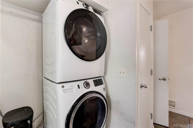 8144 Washington St Unit 192, Denver, CO 80229 - laundry area with stacked washer and clothes dryer and tile patterned flooring