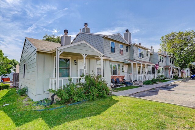 8144 Washington St Unit 192, Denver, CO 80229 - townhome / multi-family property featuring covered porch, a chimney, board and batten siding, a front yard, and a residential view
