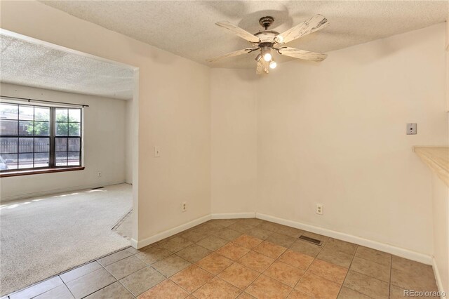 8144 Washington St Unit 192, Denver, CO 80229 - empty room with a textured ceiling, light tile patterned flooring, ceiling fan, baseboards, and light carpet