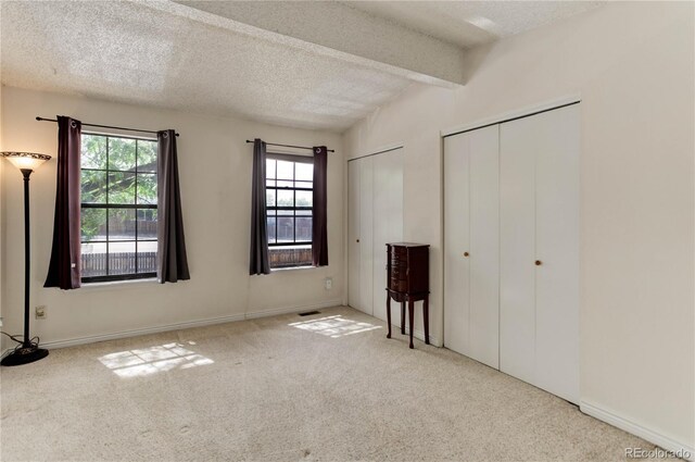 8144 Washington St Unit 192, Denver, CO 80229 - unfurnished bedroom with carpet floors, two closets, a textured ceiling, beam ceiling, and baseboards