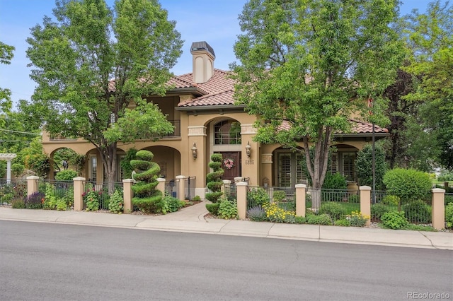 5335 E 2nd Ave, Denver, CO 80220 - mediterranean / spanish-style home with stucco siding, a fenced front yard, and a tiled roof