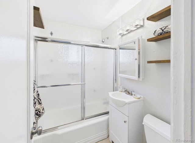 full bath with toilet, vanity, and shower / bath combination with glass door