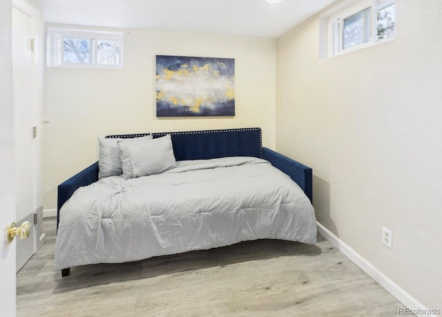 bedroom featuring baseboards, multiple windows, and wood finished floors
