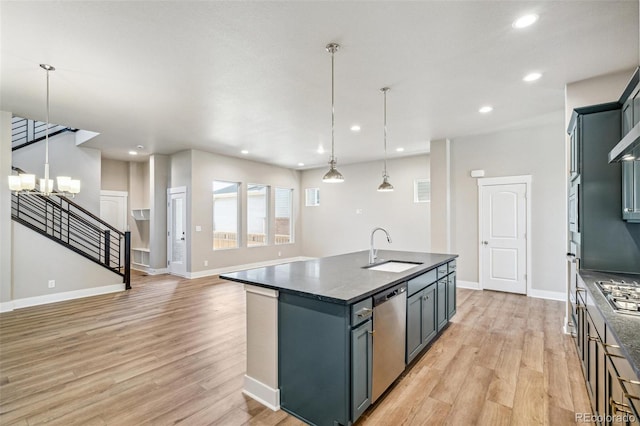 kitchen with light wood-type flooring, stainless steel appliances, a kitchen island with sink, and sink