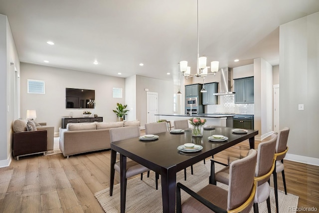 dining space featuring baseboards, recessed lighting, light wood-style flooring, and a notable chandelier