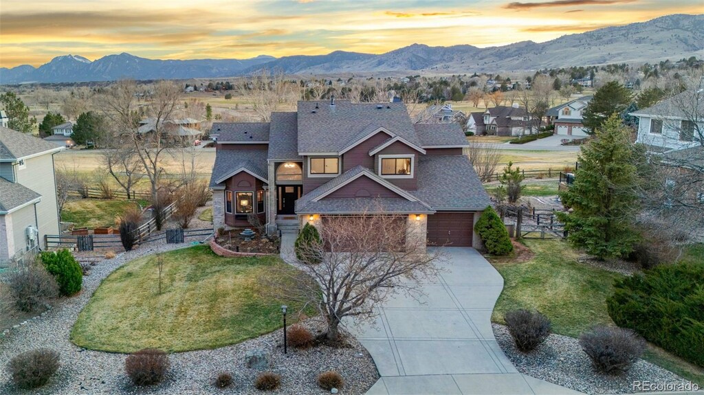 4534 Palmer Ct, Longmont, CO 80503 - view of front of home with a lawn, stone siding, fence, a mountain view, and concrete driveway