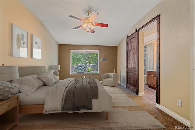 9406 Troon Village Way, Lone Tree, CO 80124 - bedroom with a barn door, vaulted ceiling, light carpet, a ceiling fan, and connected bathroom