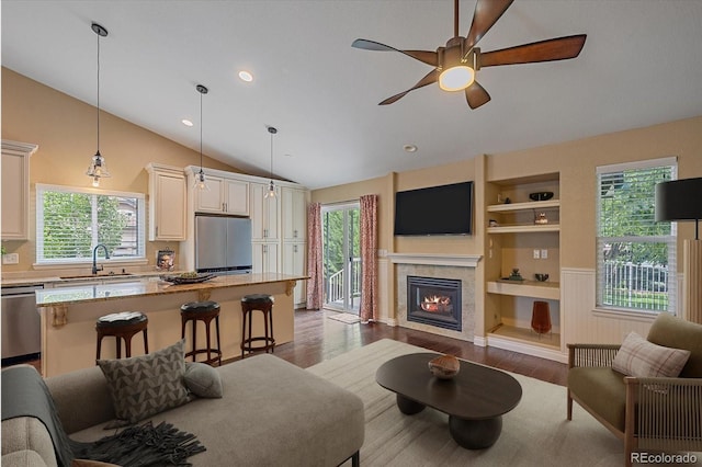 9406 Troon Village Way, Lone Tree, CO 80124 - living room featuring vaulted ceiling, wood finished floors, a ceiling fan, healthy amount of natural light, and built in shelves